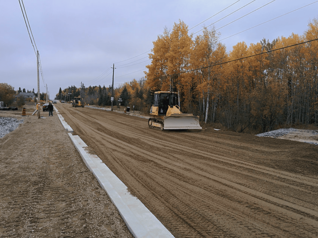 Caron Equipment Caron Equipment's civil construction team is busy grading a rural dirt road surrounded by vibrant autumn trees.