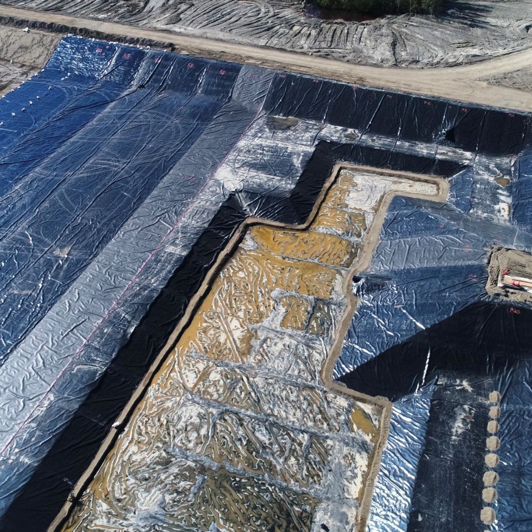 Caron Equipment An aerial view of a civil construction project reveals large tarps covering the ground, accompanied by visible rectangular excavations, exemplifying Caron Equipment's expertise in efficient site management.