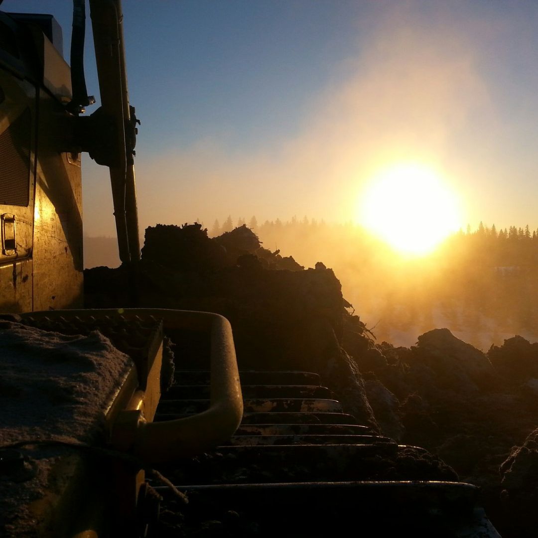 Caron Equipment At a Caron Equipment construction site, an excavator stands poised as the sun sets in the background, casting a warm glow over the scene, harmoniously blending the raw energy of civil construction with nature's serene beauty.