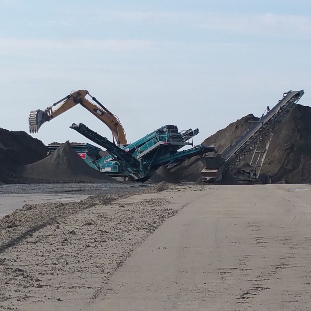 Caron Equipment Excavator and conveyor belts at a civil construction site, powered by Caron Equipment, efficiently moving and sorting piles of dirt with precision.