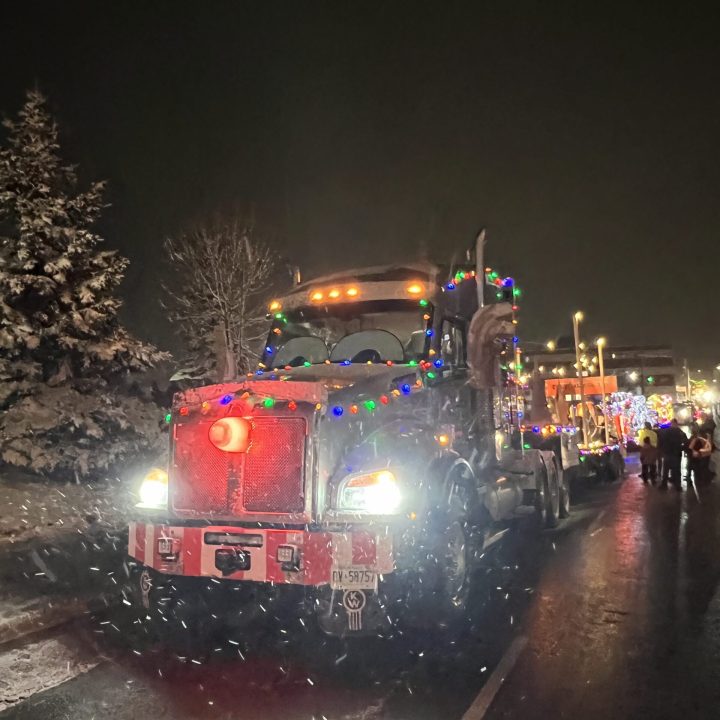 Caron Equipment A truck decorated with colorful lights and branded with Caron Equipment is parked on a wet street at night, with snow gently falling, reminiscent of the heavy-duty vehicles used in mine site construction.